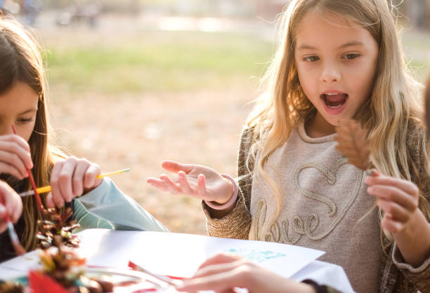 istock Cute girls coloring forest fruit in park 1128969678