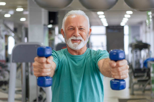 istock Senior man with barbells in gym 1128969784