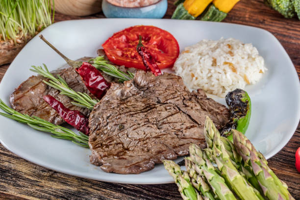 istock Medium rare beef tenderloin grilled, created background with vegetables on wooden background. 1128970441
