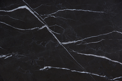 The beautiful background of natural black marble stone with white stripes, folded pattern in the form of painted mountains, is called Nero Marquina.