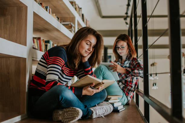 istock Two teenagers study in the library 1128971760