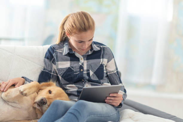 istock Girl on her tablet pets her dog 1128972998