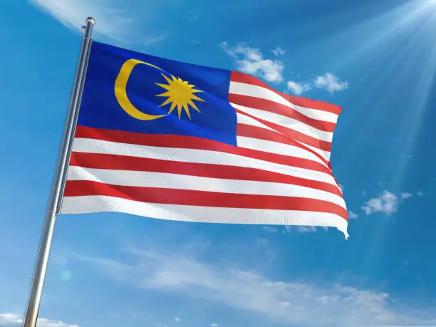 Malaysia National Flag Waving on pole against sunny blue sky background. High Definition
