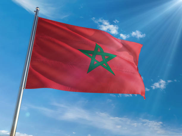 istock Morocco National Flag Waving on pole against sunny blue sky background. High Definition 1128977216