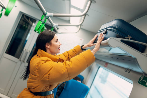 istock Young female puts luggage on the shelf railway train. 1128981113