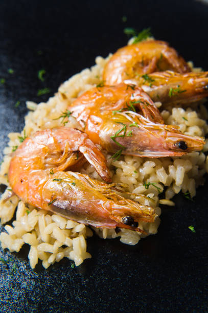 istock Italian risotto with shrimp on a black plate. Dark background, top view, close up. 1128986448