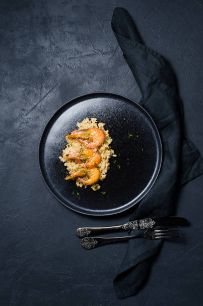 istock risotto with shrimp on a black plate. Dark background, top view 1128987161
