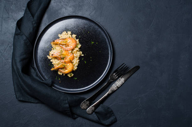 istock Italian risotto with shrimp on a black plate. Dark background, top view 1128987162