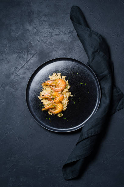 istock risotto with shrimp on a black plate. Dark background, top view 1128987328