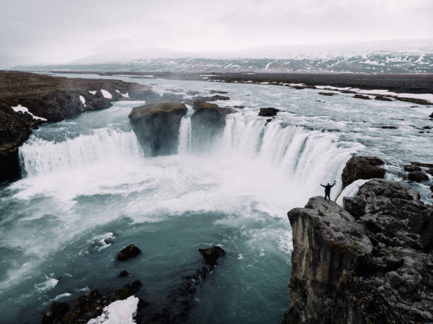 istock Drone shot of waterfall with man on the edge 1128987416