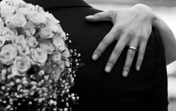 Bride hand and bouquet - black and white Bouquet, bride's hand with wedding ring on the groom's shoulder. sposa stock pictures, royalty-free photos & images