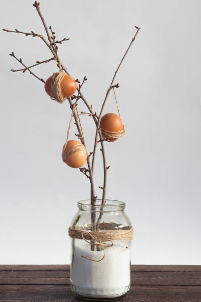 Easter eggs hanging on branches in the glass jar