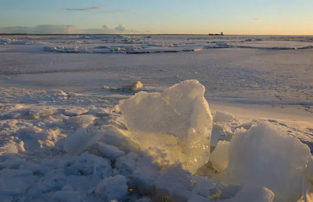Photo of Melting pieces of thick ice on frozen sea at sunset time