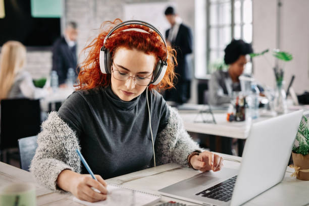istock Young businesswoman taking notes while working on laptop in the office. 1128990738