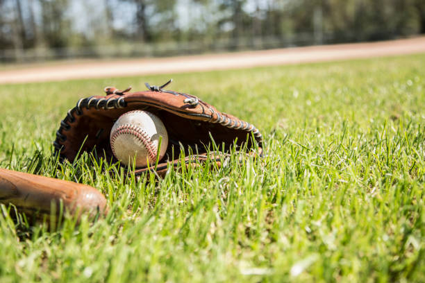 бейсбольный сезон здесь.  летучая мышь, перчатка и мяч на поле. - baseball spring training baseballs sports glove стоковые фото и изображения