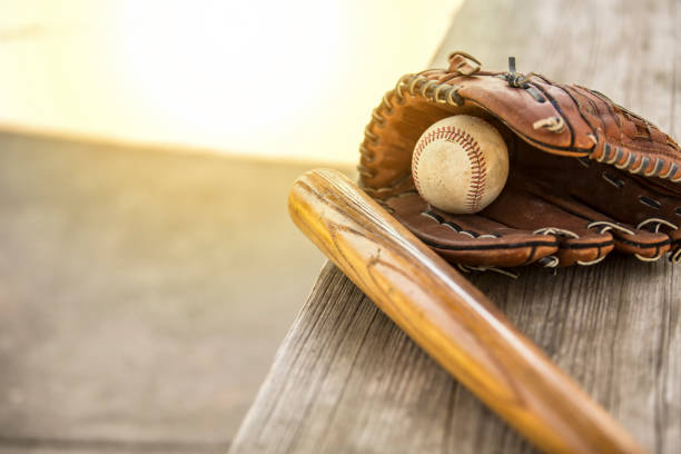бейсбольный сезон здесь.  летучая мышь, перчатка и мяч на скамейке блиндажа. - baseball spring training baseballs sports glove стоковые фото и изображения
