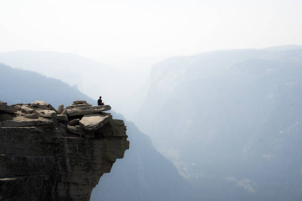 Yosemite Valley in Smoke, Half Dome Hiker admires the smokey views of Yosemite Valley, seen from the Half Dome "diving platform" at Yosemite National Park, California. pacific crest trail stock pictures, royalty-free photos & images