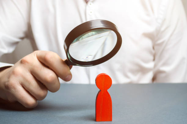 istock Businessman examines a red man through a magnifying glass. Search for unreliable employee. Weak link. Diagnosis of psychological and physical diseases. Toxicity in the staff of workers. Sabotage 1128991769