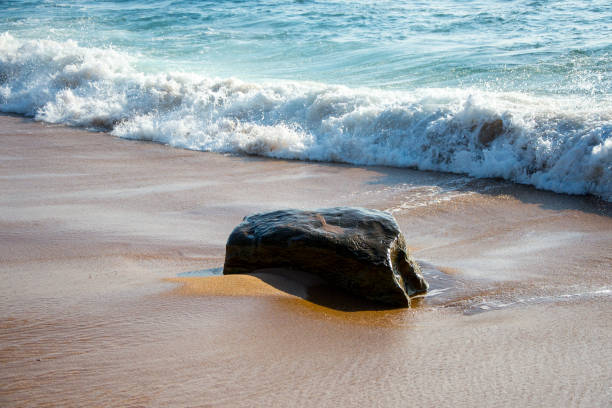 istock Colors and textures of ocean waves hitting beach stone 1128996967