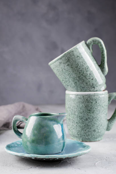 istock Country, rustic style handcraft kitchenware. Blue ceramic cream jug and two porcelain cup on grey background 1128997031