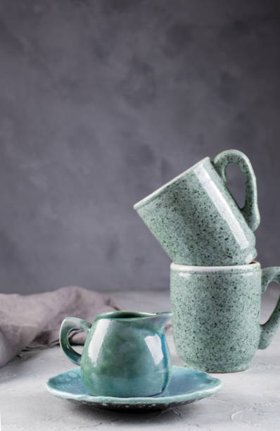 istock Country, rustic style handcraft kitchenware. Blue ceramic cream jug and two porcelain cup on grey background 1128997034