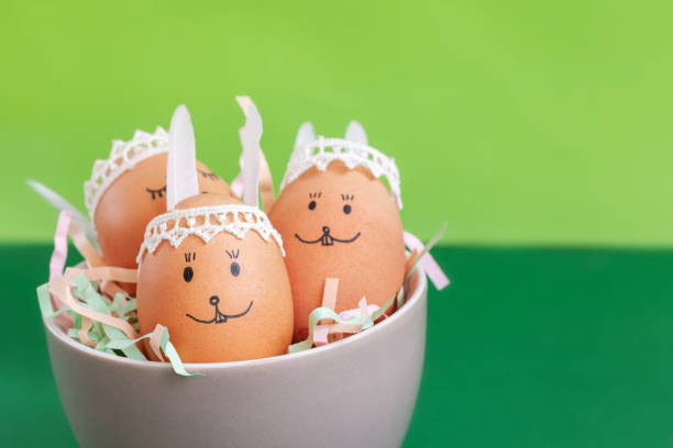 istock Funny easter bunnies eggs in bowl on green paper background . Happy Easter concept. 1128999028