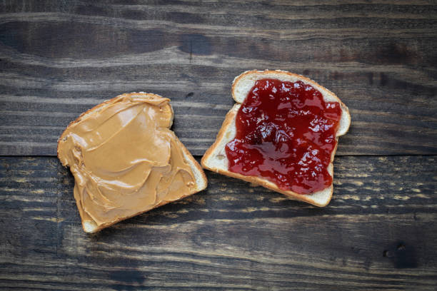 Open face homemade peanut butter and strawberry Jelly sandwich Top view of open face homemade peanut butter and strawberry Jelly sandwich on oat bread, over a rustic wooden background. peanut butter and jelly sandwich stock pictures, royalty-free photos & images