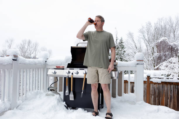 reifer mann immer bereit zum grillen beim biertrinken während der wintersaison - shorts stock-fotos und bilder