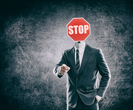 Stop sign as head on businessman in a suit pointing at you - Image manipulation