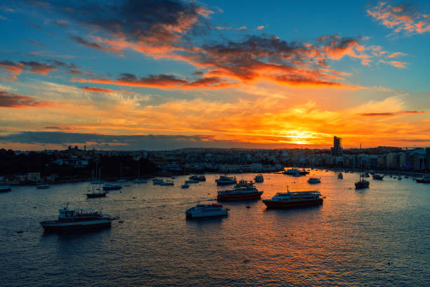 Ships and boats in the bay during beautiful sunset in city of Sliema, Malta.