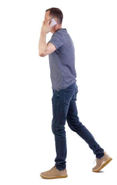 istock a side view of man walking with a mobile phone. 1129015380
