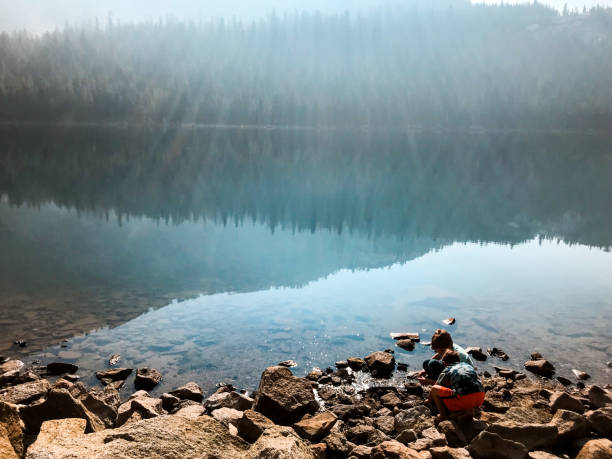 istock Children play by a lake with a beautiful reflection in the mountains 1129019948