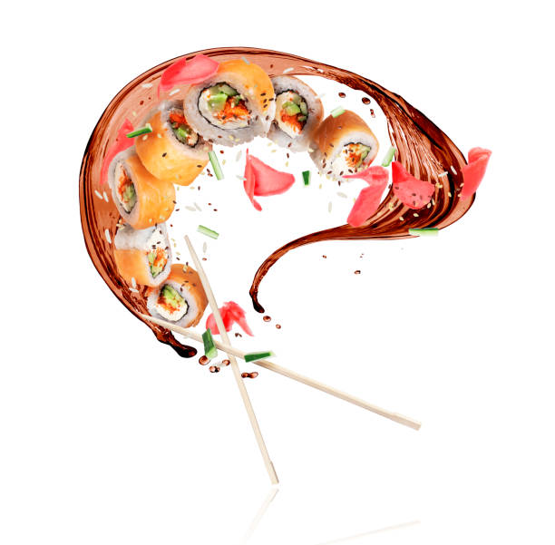 Fresh sushi rolls with splashes of soy sauce, frozen in the air on white background