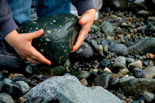 istock Child Helping Father Lift Rock 1129026031