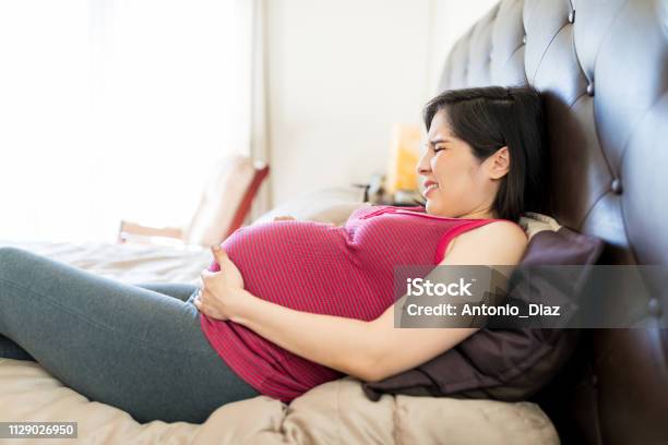 Woman Suffering From Braxton Hicks Contractions Stock Photo - Download Image Now - Muscular Contraction, Labor - Childbirth, Domestic Life