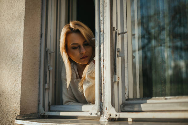 istock Sad woman looking through the window 1129028972