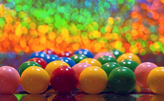 Many colors round bubble chewing gums with reflections  on a mirror on a bokeh multi-colored glowing background