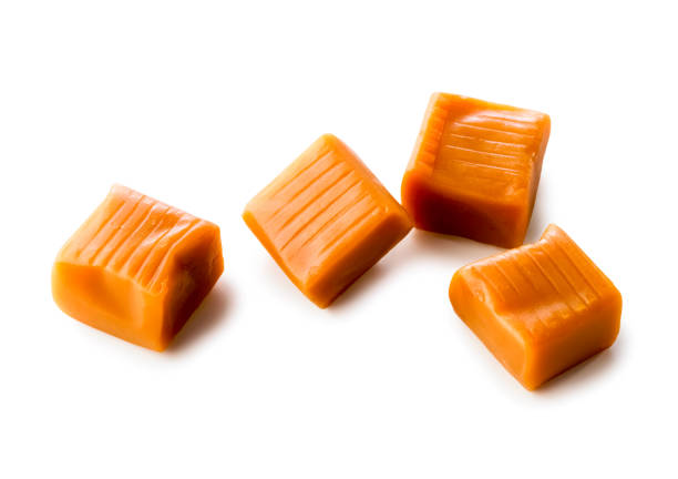 vier toffee karamell bonbons nahaufnahme isoliert auf weißem hintergrund (mit clipping-pfad) - taffy stock-fotos und bilder