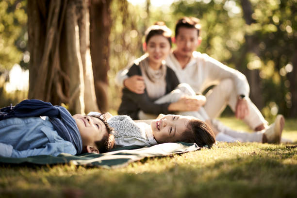 istock happy asian family relaxing in park 1129041098