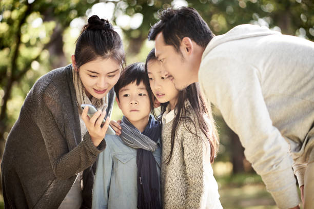 asian family using mobile phone outdoors