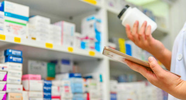 istock Pharmacist holding medicine and computer tablet in pharmacy 1129043611