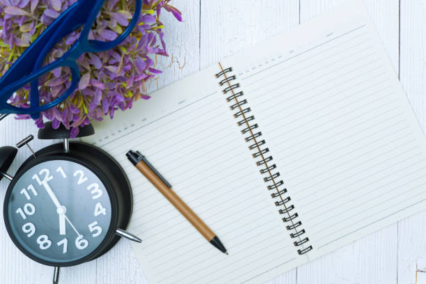 istock Blank notebook paper and glasses with pen and office supplies, top view. 1129048982