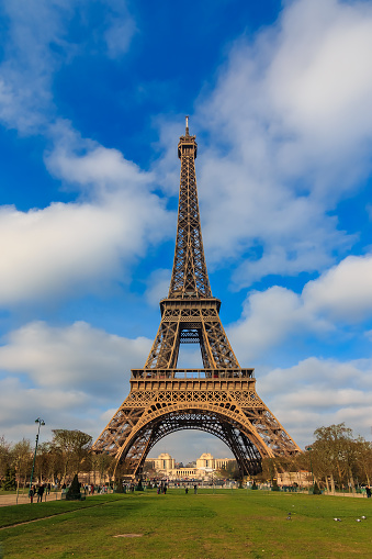 View of the Eiffel Tower or Tour Eiffel seen from Champ de Mars in Paris, France on a beautiful cloudy day