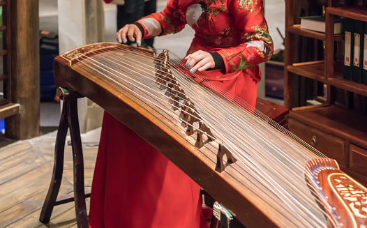 The girl is playing a guqin in a tea house in Chongqing, China.
