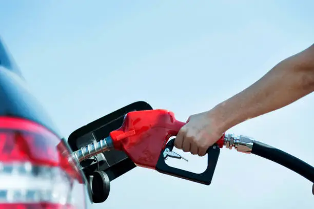 Man hand holding fuel pump and refilling car