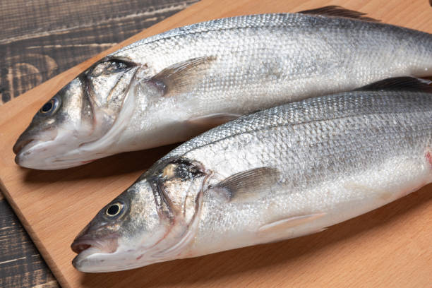 istock two fresh fish on a wooden cutting board, close-up shooting 1129065145