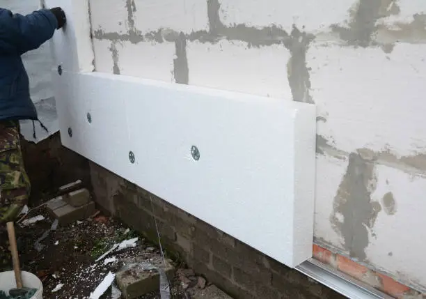 Photo of Building contractor insulating House Wall with styrofoam insulation sheets.