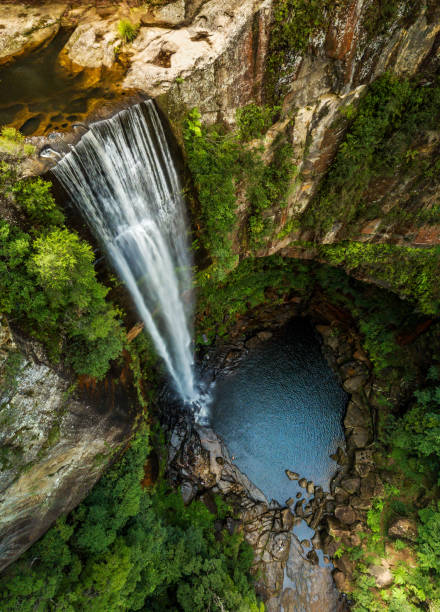 istock Tumbling waterfall into idyllic rock pool at bottom of cliffs 1129069328