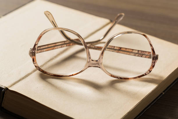 istock old book open on a wooden table with glasses 1129069439