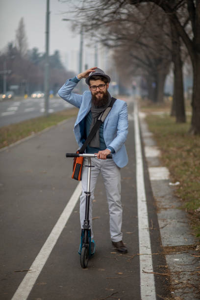 istock Young businessman with a beard smiling on kick scooter 1129070968